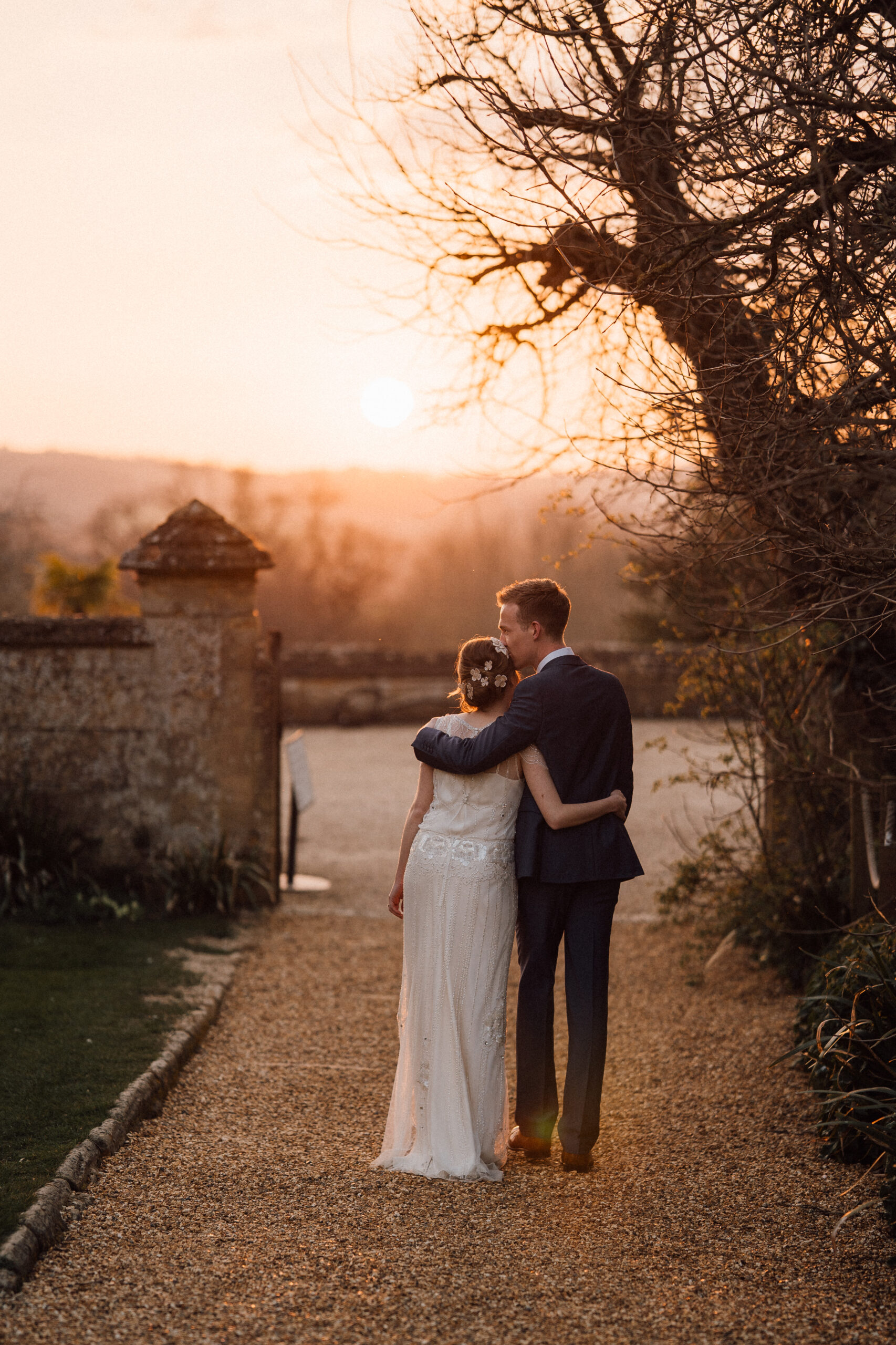 Wedding couple walks toward sunset at Sudeley Castle