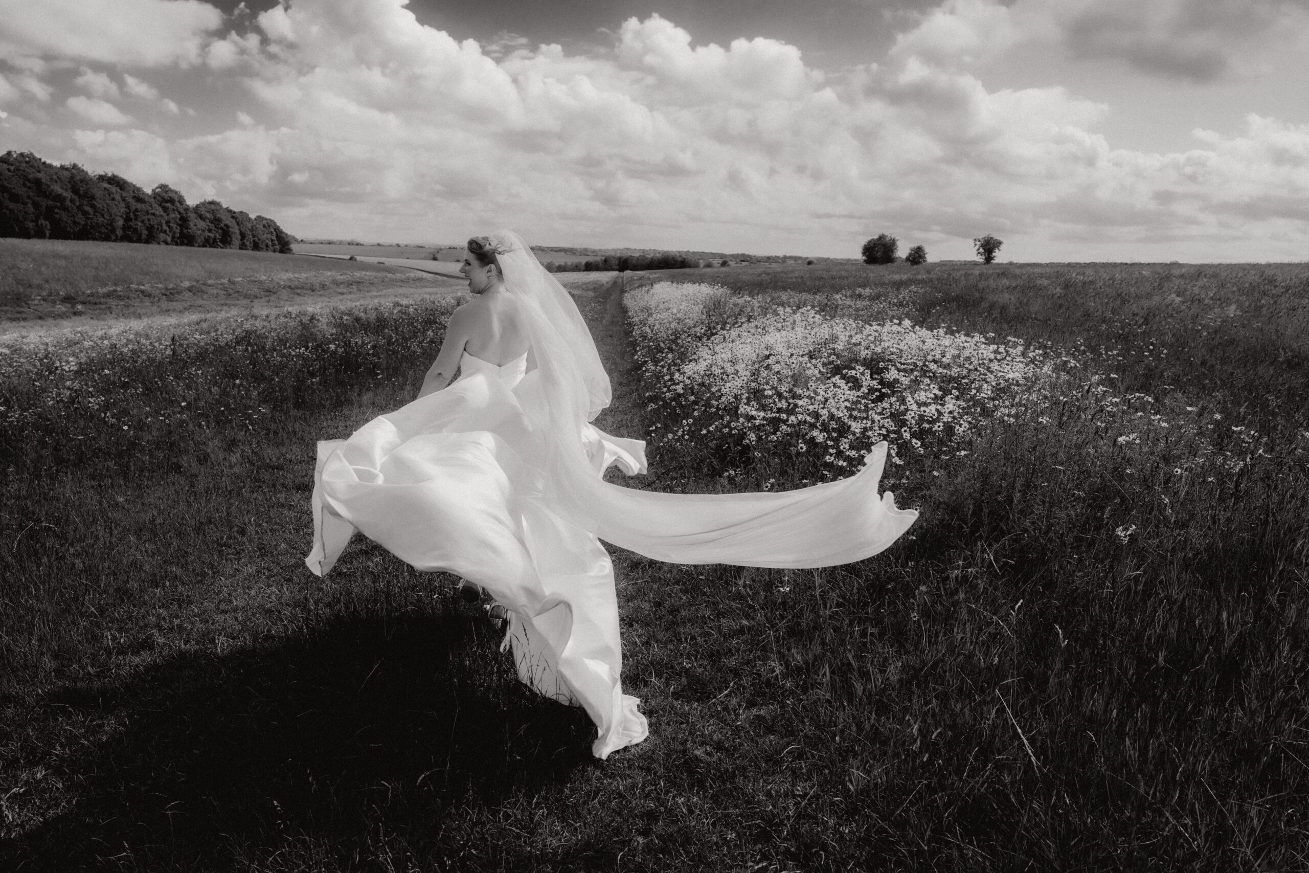 bride running away from camera at stone barn, cotswolds